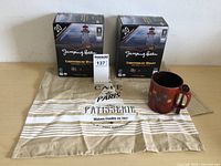 The full lot with two coffee boxes, tea towel, coffee cup and spoon on display.