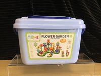 Light blue plastic storage container with label 'TEMI Flower Garden Free Assembly 138 Pieces'.