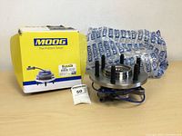Photo of the MOOG wheel bearing and hub assembly beside its yellow and blue branded box and protective packaging.