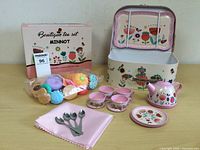 Full view of the tea set with carrying case, teapot, cups, spoons, plate, napkin, and toy food bag visible.