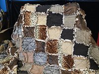 Front side detail of the rag quilt displaying various fabric squares including leopard print, solid colors, stripes, and textured fabrics with ragged seams.