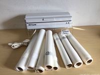 DecoSonic food sealer machine with eight rolls of transparent sealer bags displayed on wooden surface.