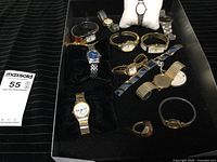 Collection of assorted watches in a black lined box with paper MaxSold tag to the side