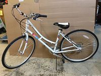 Side profile of white women’s bicycle with step-through frame, Supercycle branding, 26" wheels and kickstand deployed
