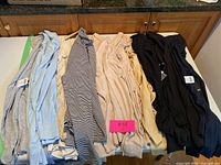 10 ladies turtle neck tops folded and laid out on white surface, showing various colors including gray, blue, beige, black, and black and white stripes.