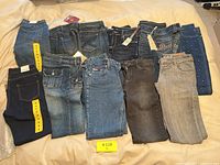 All 11 pairs of jeans laid flat, showing different washes and styles including bootcut, skinny and flare.