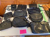 Overview of all 11 black leather and vegan leather purses arranged on table showing variety of styles and sizes