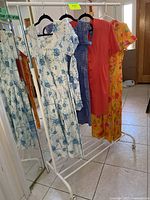 Four vintage floral dresses hanging on clothing rack showing arrangement and styles.
