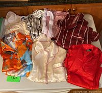 Seven silky women's pajama pieces in varied colors and patterns spread on a flat surface.