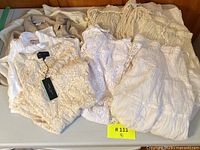 Nine pieces of white and cream boho skirts and tops laid out on table