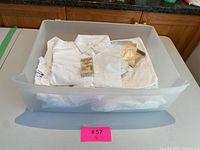 White button-down shirts neatly placed inside a plastic container showing multiple garments.