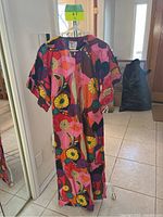 Front view of the maxi dress on hanger, showing vivid flower power pattern and zip front.