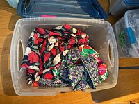 Plastic storage bin with three vintage floral skirts inside, showing colors and prints.