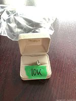Ring displayed inside an open beige jewelry box with a green sticker labeled '10K'.