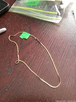 Full length view of gold chain laid out on wooden surface