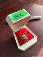 Starburst pendant pin displayed in its hinged jewelry box