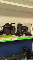 Full lot on shelf showing camera body, extension tubes manual, pentaprism viewfinder, two lenses and hoods