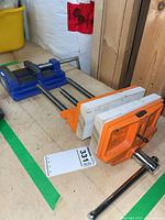 Forge 4 inch blue drill press vice and orange Pony clamp on wooden bench