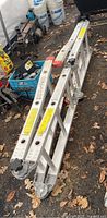 Combination ladder folded and placed on ground, aluminum frame with visible hinges and feet caps.