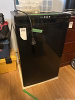 Front view of black Danby Silhouette bar fridge with attached power plug.