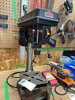 Full view of Job Mate drill press on a workbench with power cord, metal base, and control lever visible.
