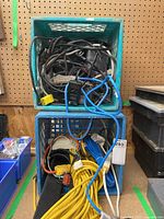 Stacked blue milk crates filled with various electrical cords and power bars