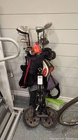 Full view of black golf bag standing upright with assorted golf clubs, including the metal heads and some club headcovers visible.