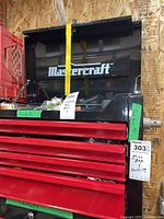 Front view showing black hinged lid open above four red drawers