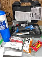 Porter Cable PIN 138 nailer and BeA pneumatic nailer in black plastic carry case with packs of nails and a blue gas canister. Instruction manuals visible.