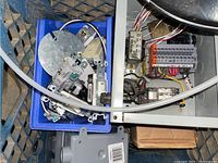 Blue crate with multiple electrical switches and switch plates including toggle and rocker switches, metal conduit parts visible.