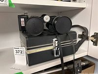 Binoculars resting on closed black carrying case with metal lock, strap attached.