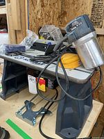 Overview of router mounted to table, cords and accessories visible