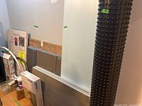 Overall view showing foam and tile boards stacked, drainage membrane roll at right and small adhesive containers left