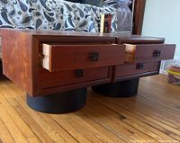 Pair of teak bedside tables side by side with top drawers open.