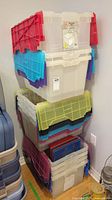 Stack of clear plastic storage bins with colored double folding lids