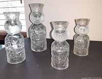 Four vintage crystal glass candle holders shaped as kings by Bjorn Wiinblad, arranged on dark surface.