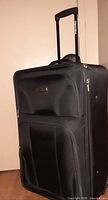 Front view of black Tracker suitcase with telescopic handle extended, showing multiple front pockets and sturdy structure.