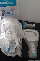 Photo of AquaSense bath safety rail components wrapped in bubble wrap, including main rail and handle parts.
