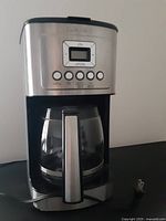 Frontal close-up showing control buttons, digital screen, and glass carafe with handle.