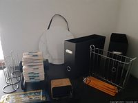View showing vintage Rolodex with refill cards, round white magnetic bulletin board, black file box, chrome wire letter holder, wooden pencil holder, and black metal bookends.