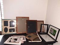 Various picture frames and picture frame mats arranged on table, showing different sizes and styles.