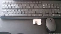 Top-down view showing Logitech wireless keyboard and mouse with USB receiver on a dark surface