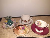 Photo showing four bone china cups and saucers alongside the cobalt blue silver gilded bud vase on a cloth background.