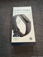 Front view of sealed Fitbit Charge 4 box showing product name, image and main features.