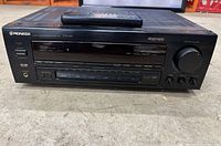 Front view of black Pioneer VSX-453 receiver with remote control placed on top, showing buttons, display panel, and volume knob.