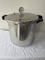 Front view of the large aluminum pressure canner with lid and pressure gauge showing overall condition and handles.