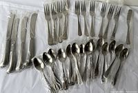 Flatware set laid out showing knives, forks, and spoons