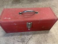 Closed red metal toolbox with chrome handle and latch, shows wear and scuff marks