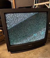 Front view of Toshiba 32 inch CRT TV powered on showing static screen.