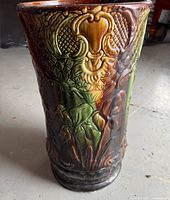Front view showing embossed floral and lattice patterns with yellow, brown, and green glaze.